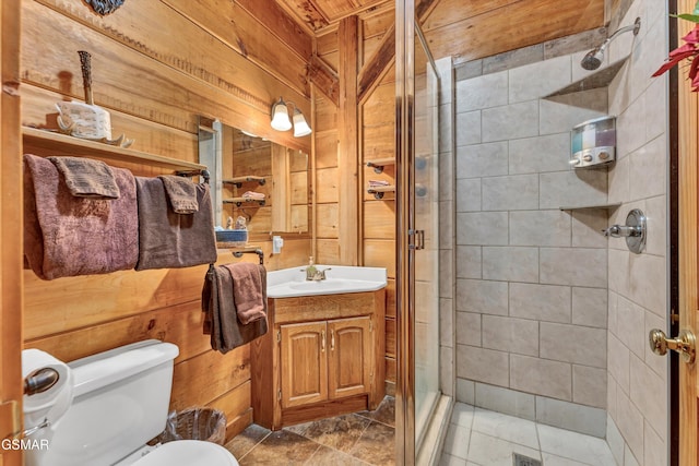 bathroom with vanity, toilet, a shower with shower door, and wood walls