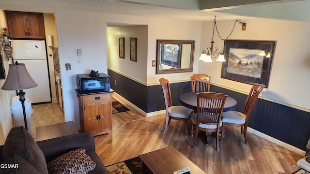 dining room with hardwood / wood-style floors, a textured ceiling, and a notable chandelier