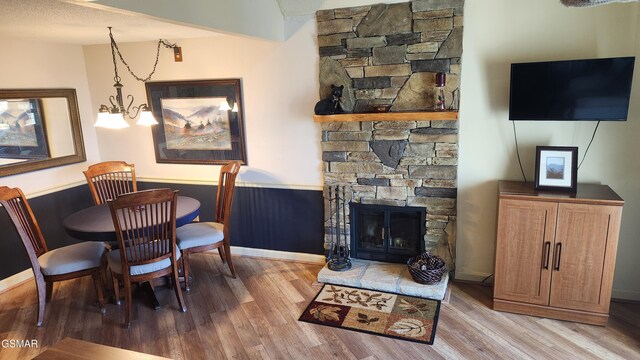 dining space featuring a fireplace, light wood-type flooring, and an inviting chandelier