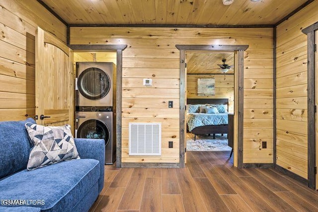 sitting room with wood ceiling, stacked washer / dryer, dark wood finished floors, and visible vents