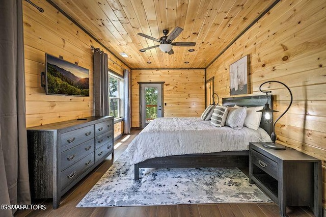 bedroom with dark wood-style floors, access to outside, wooden ceiling, and wooden walls