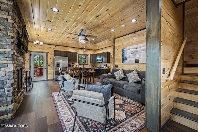 living area with wooden walls, dark wood-type flooring, a fireplace, wood ceiling, and stairs