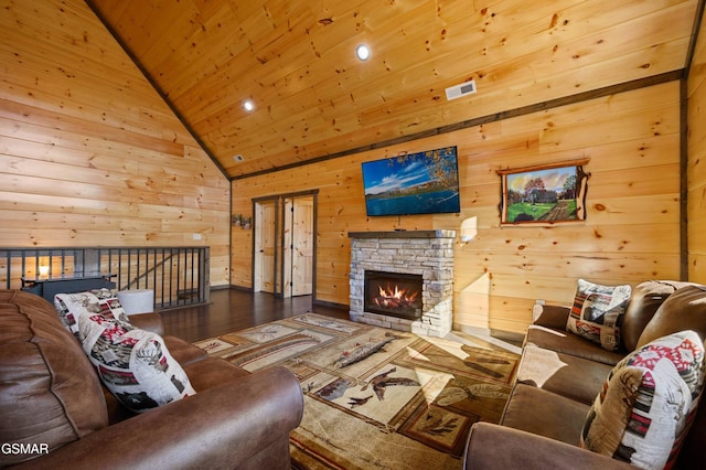 living room featuring visible vents, wooden ceiling, wood finished floors, a stone fireplace, and wood walls