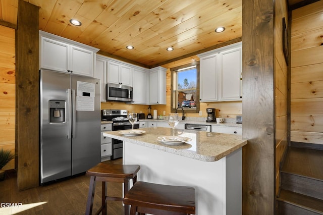 kitchen featuring a breakfast bar area, wooden ceiling, white cabinetry, appliances with stainless steel finishes, and a center island