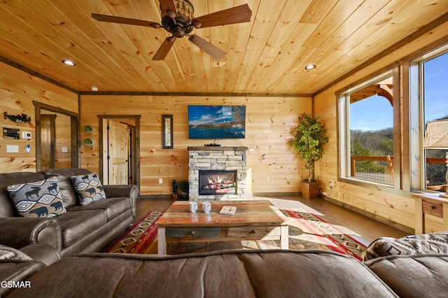 living area featuring wood ceiling, wood finished floors, a stone fireplace, wood walls, and recessed lighting