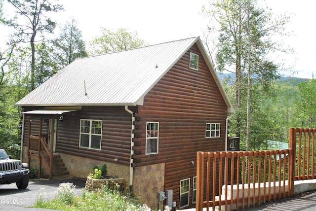 view of home's exterior featuring log siding, metal roof, and a deck