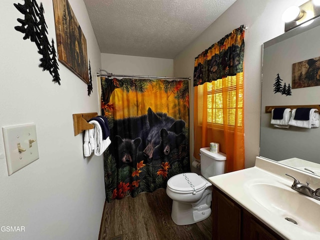 bathroom featuring vanity, wood finished floors, curtained shower, toilet, and a textured ceiling