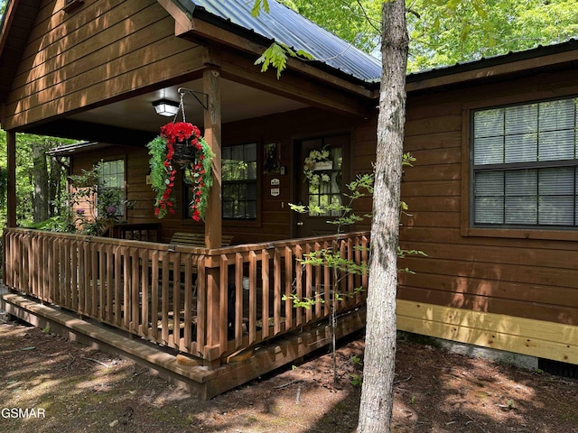 doorway to property featuring a porch and metal roof