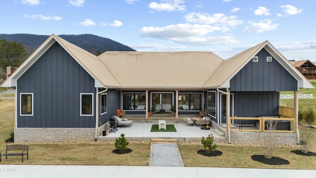 back of property featuring board and batten siding, metal roof, a patio, and a mountain view