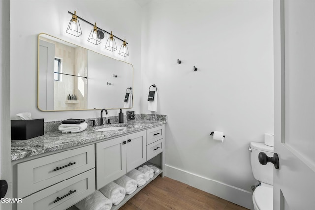 bathroom with wood finished floors, vanity, toilet, and baseboards