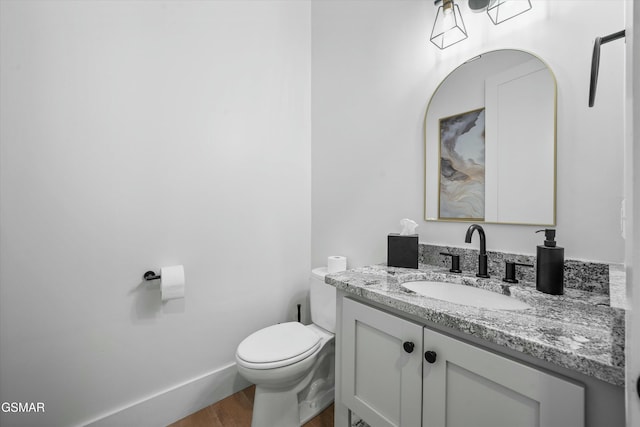 bathroom featuring baseboards, vanity, toilet, and wood finished floors