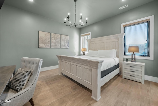 bedroom featuring a chandelier, light wood-type flooring, visible vents, and baseboards