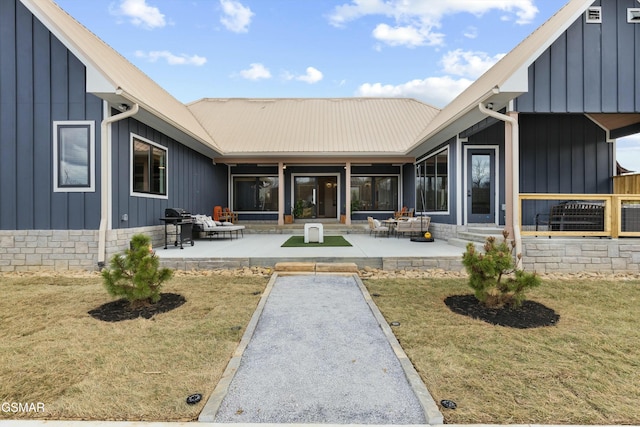 rear view of property with metal roof, a patio, and board and batten siding