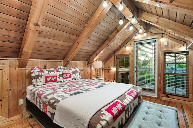 bedroom with lofted ceiling with beams, wood walls, access to exterior, and hardwood / wood-style floors