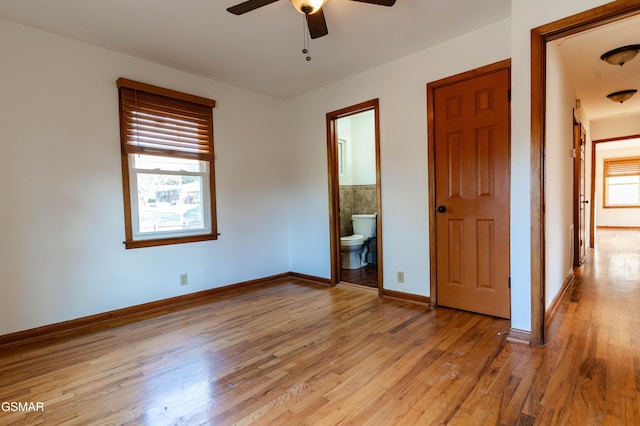 unfurnished bedroom featuring baseboards, ensuite bathroom, and light wood-type flooring