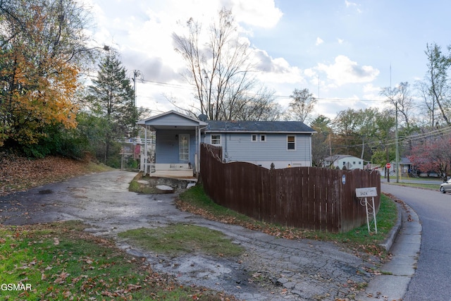 view of front of property featuring a porch, aphalt driveway, and fence