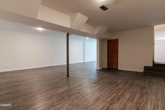 finished below grade area with baseboards, visible vents, and dark wood-type flooring