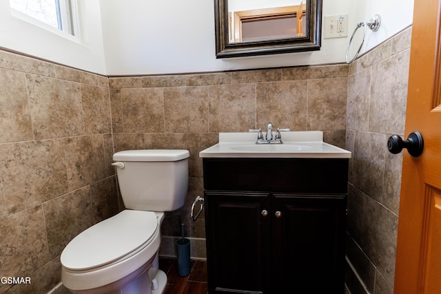 bathroom with wainscoting, tile walls, vanity, and toilet