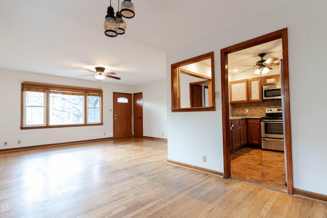 unfurnished living room featuring baseboards, ceiling fan, and light wood-type flooring