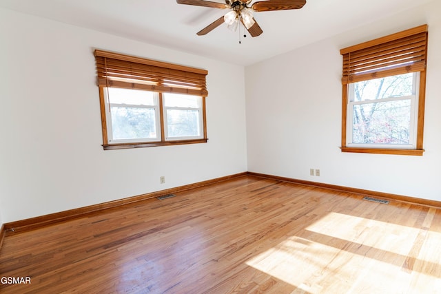 spare room featuring ceiling fan, baseboards, visible vents, and wood finished floors