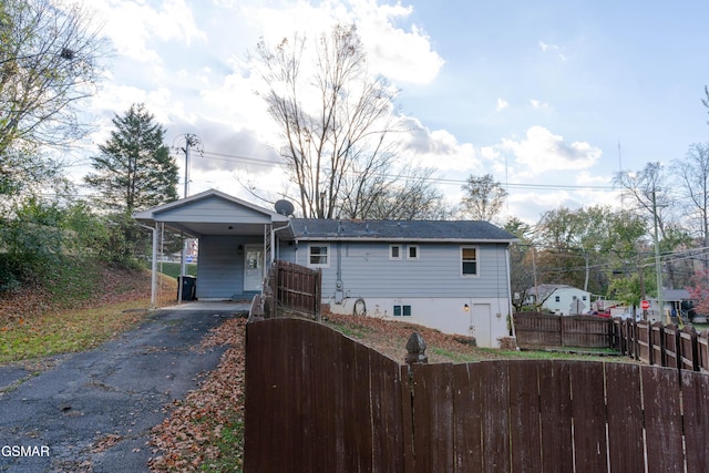 view of front of home featuring fence private yard, aphalt driveway, and an attached carport