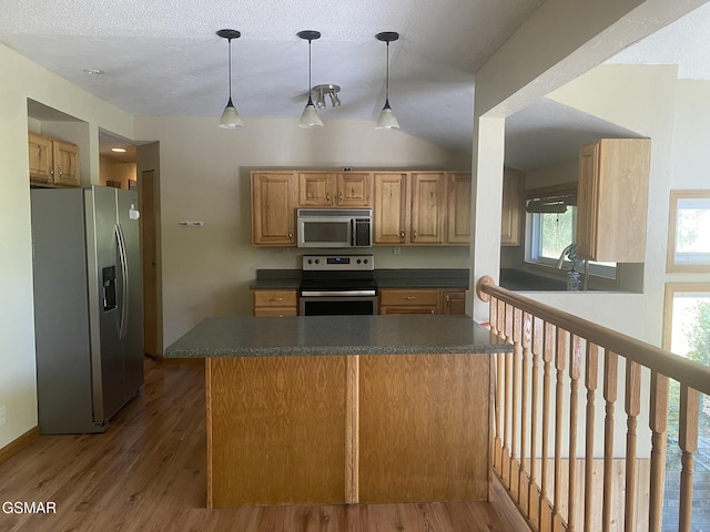 kitchen with pendant lighting, dark hardwood / wood-style flooring, kitchen peninsula, and stainless steel appliances