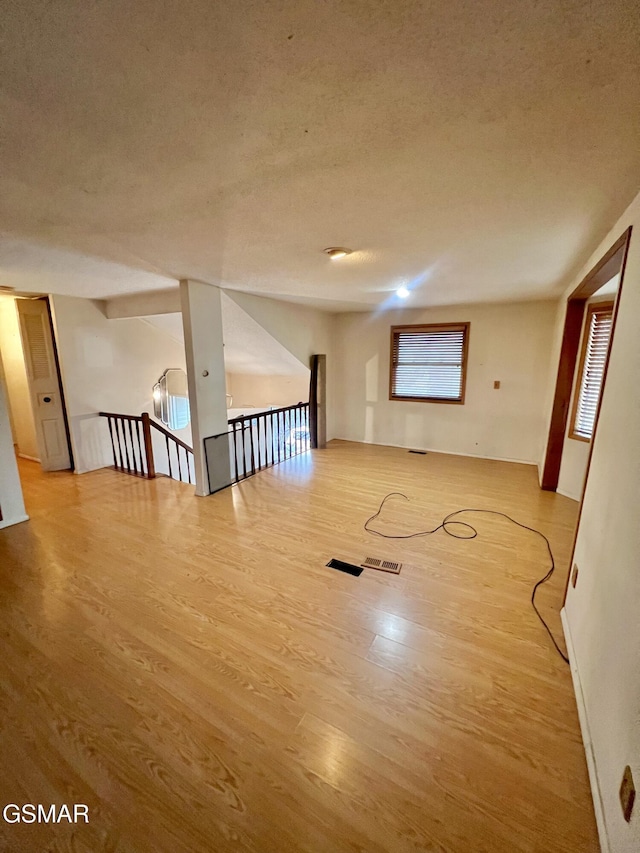 unfurnished room with wood finished floors, visible vents, and a textured ceiling