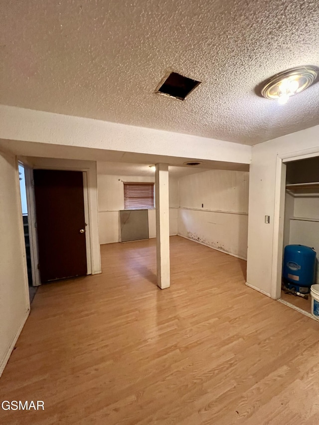 finished below grade area with a textured ceiling and light wood-style flooring