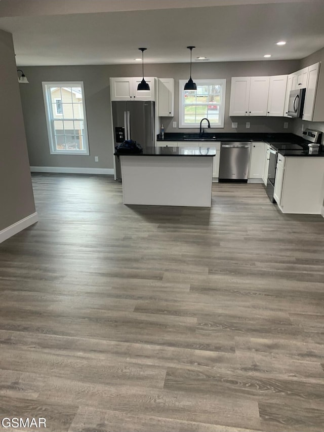 kitchen with appliances with stainless steel finishes, light wood-type flooring, sink, decorative light fixtures, and white cabinetry