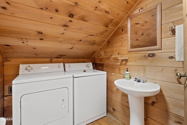 laundry room featuring light wood-style flooring, wood walls, laundry area, washer and dryer, and wooden ceiling