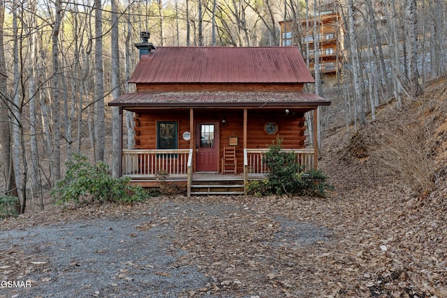 view of front of property with a porch, metal roof, a chimney, and log siding