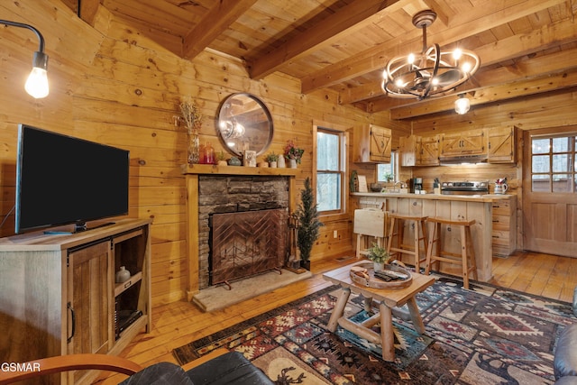 living area with wooden ceiling, wood walls, light wood-style flooring, and beamed ceiling