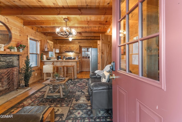 living area featuring a chandelier, wooden ceiling, hardwood / wood-style flooring, wood walls, and beamed ceiling