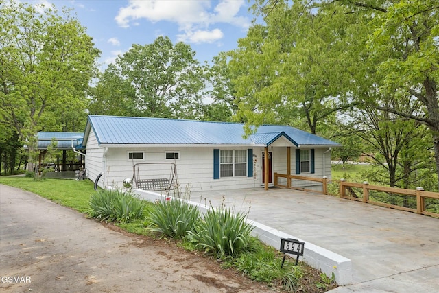 view of front of home featuring driveway, fence, and metal roof