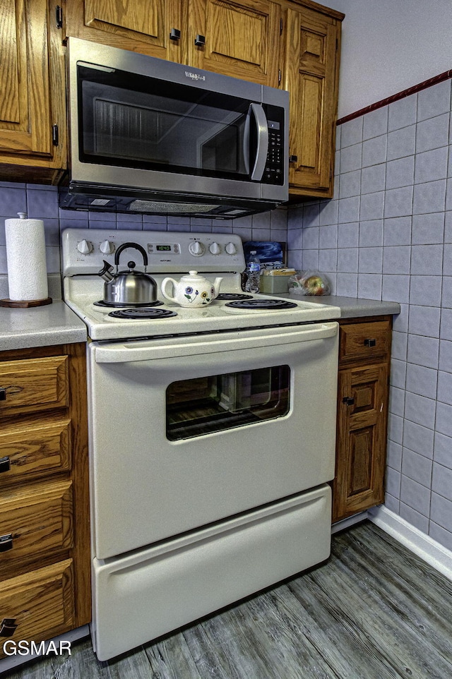 kitchen with decorative backsplash, hardwood / wood-style floors, white electric range oven, and tile walls