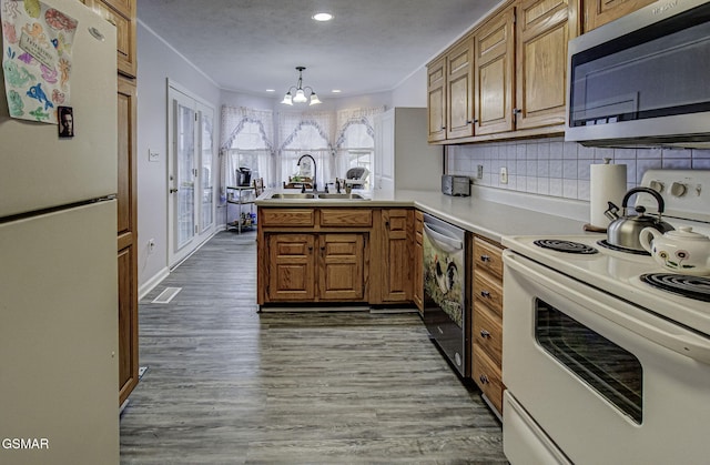 kitchen with kitchen peninsula, stainless steel appliances, sink, pendant lighting, and an inviting chandelier