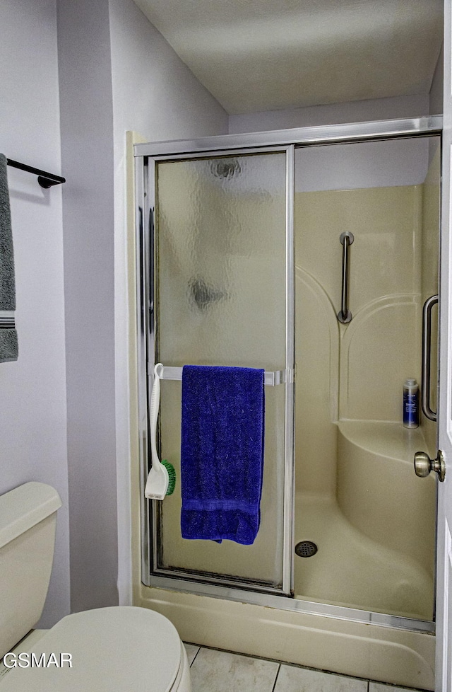 bathroom with tile patterned floors, an enclosed shower, and toilet