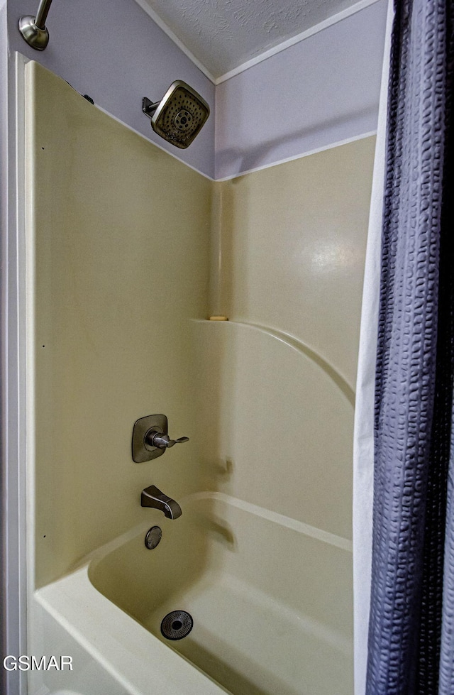 bathroom with shower / bathtub combination with curtain and a textured ceiling