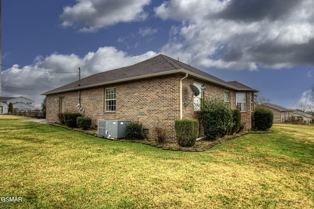 view of side of property featuring central AC unit and a lawn