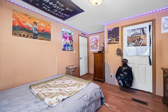 bedroom with wood-type flooring and a textured ceiling