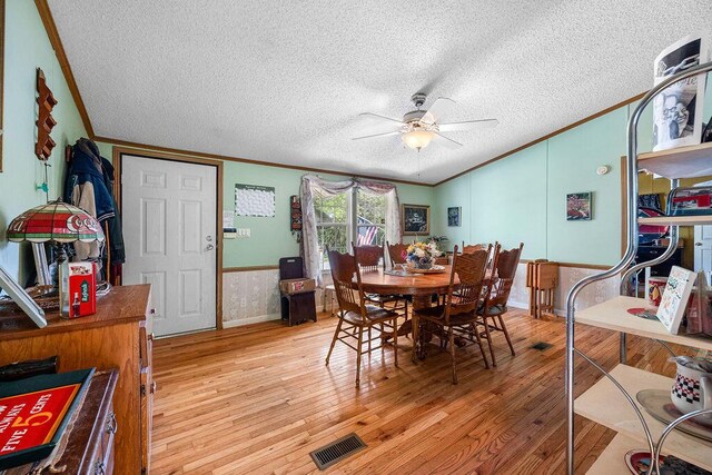 dining area with ceiling fan, crown molding, a textured ceiling, and light wood-type flooring