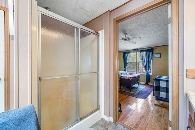 bathroom featuring ceiling fan, wood-type flooring, a textured ceiling, and walk in shower