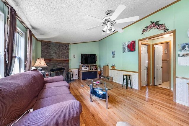 living room featuring hardwood / wood-style flooring, a brick fireplace, ceiling fan, and ornamental molding