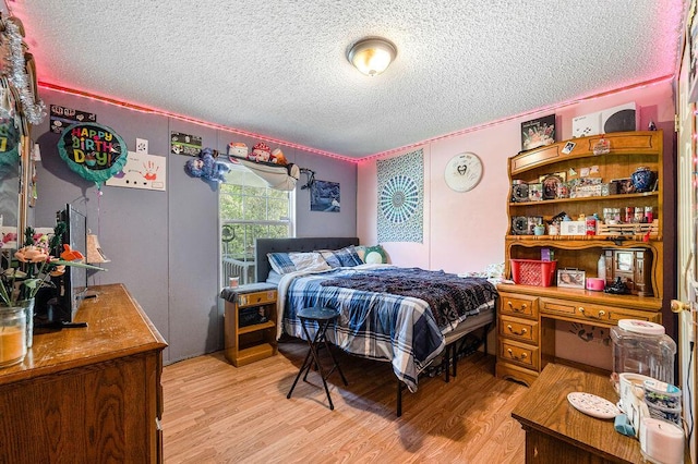 bedroom with light hardwood / wood-style floors, a textured ceiling, and ornamental molding