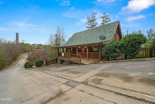 view of front of property with a porch, roof with shingles, and fence