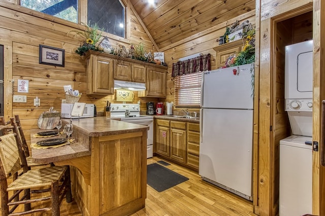 kitchen featuring kitchen peninsula, a kitchen breakfast bar, white appliances, stacked washer and clothes dryer, and lofted ceiling