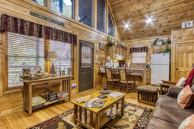 living room featuring light hardwood / wood-style flooring, high vaulted ceiling, wooden ceiling, and wood walls