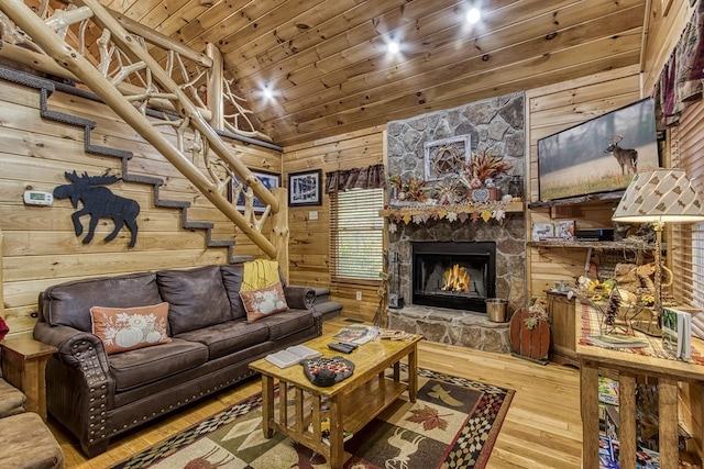 living room featuring wood ceiling, a stone fireplace, wood walls, and wood-type flooring