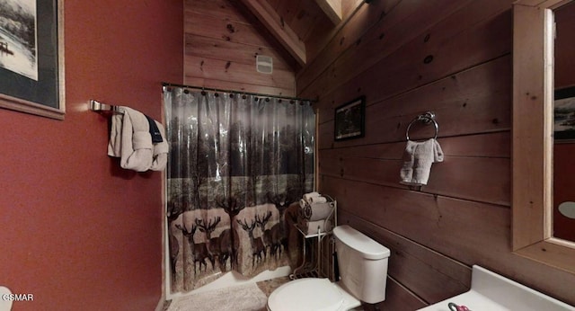 bathroom featuring toilet, lofted ceiling, and wood walls