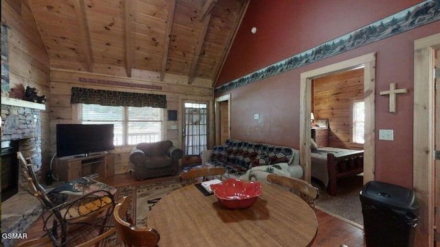 living room featuring hardwood / wood-style flooring, high vaulted ceiling, wooden ceiling, beamed ceiling, and a stone fireplace